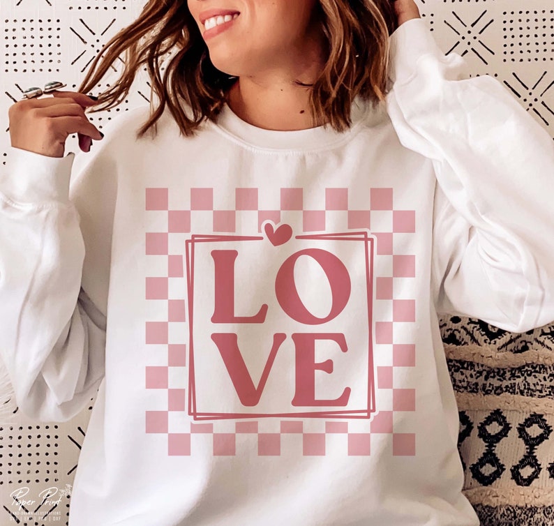 May include: White sweatshirt with a pink and white checkered pattern and the word "LOVE" in pink letters.