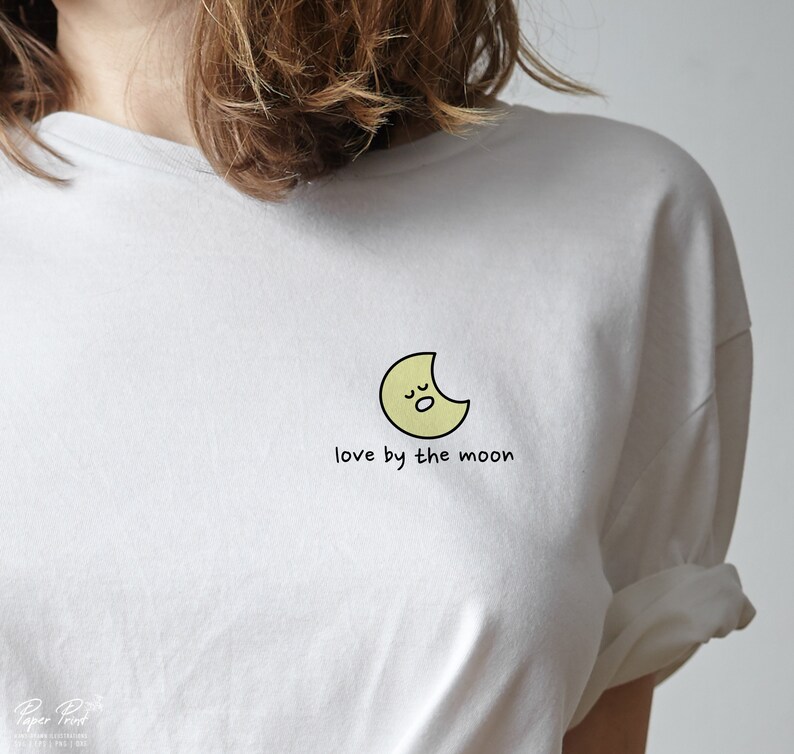May include: White t-shirt with a yellow crescent moon graphic and the text "love by the moon".