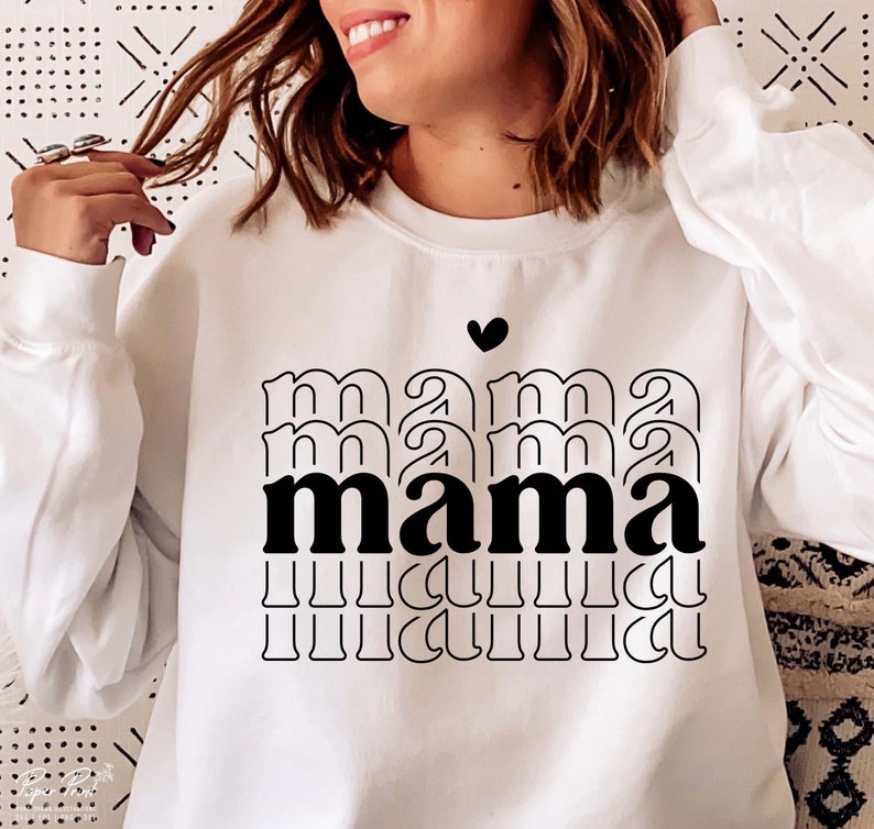 May include: White sweatshirt with a black graphic design that says "mama" in a stacked, layered font. A small black heart is above the word.