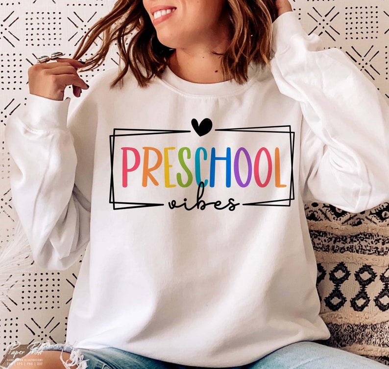 May include: White sweatshirt with a rainbow colored "PRESCHOOL vibes" graphic and a black heart.