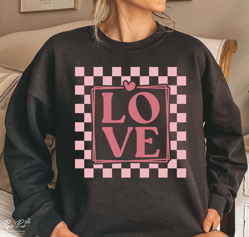 May include: Black sweatshirt featuring a pink checkered pattern and the word "LOVE" in a pink box.