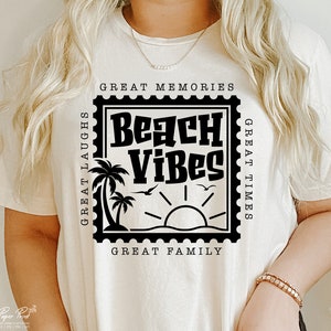 Puede incluir: Camiseta blanca con un gr&aacute;fico negro de un sello con el texto "Beach Vibes" en su interior. El sello tiene el texto "Great Memories", "Great Times" y "Great Family" alrededor del borde.
