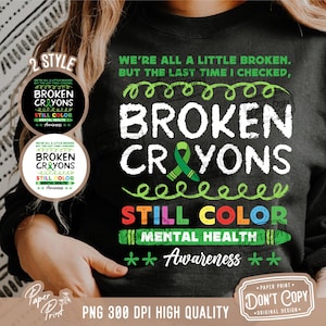 May include: A black t-shirt with the text "We're all a little broken. But the last time I checked, broken crayons still color." The text is in white with green, yellow, and red accents. The text is surrounded by a green, yellow, and red crayon border. The text "Mental Health Awareness" is also included in the design.