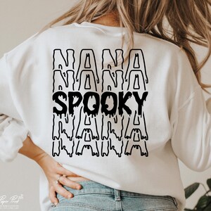 May include: White sweatshirt with a black graphic design that says "Spooky Nana" with the word "Nana" repeated three times.