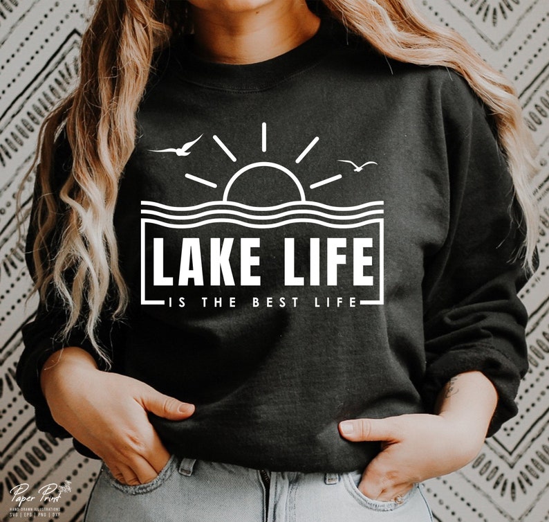 May include: Black sweatshirt with a white graphic that reads "LAKE LIFE IS THE BEST LIFE." The design includes a sun, waves, and two birds. The sweatshirt is a crew neck style.