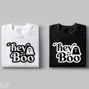 May include: Two folded t-shirts with a black and white graphic design. The design features the text "They Boo" with a ghost next to the word "Boo". One shirt is white and the other is black.