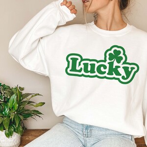 May include: White sweatshirt with a green shamrock and the word "Lucky" in a green retro font.