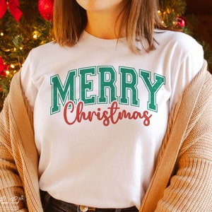 K&ouml;nnte beinhalten: Wei&szlig;es T-Shirt mit einem gr&uuml;n-wei&szlig;en "Frohe Weihnachten"-Motiv.