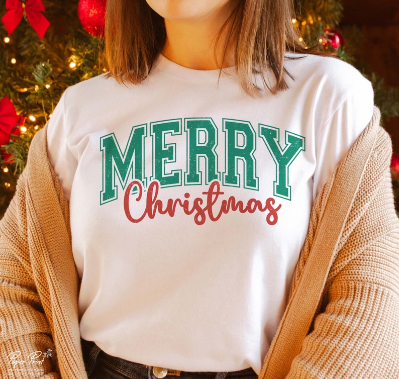 K&ouml;nnte beinhalten: Wei&szlig;es T-Shirt mit einem gr&uuml;n-wei&szlig;en "Frohe Weihnachten"-Motiv.