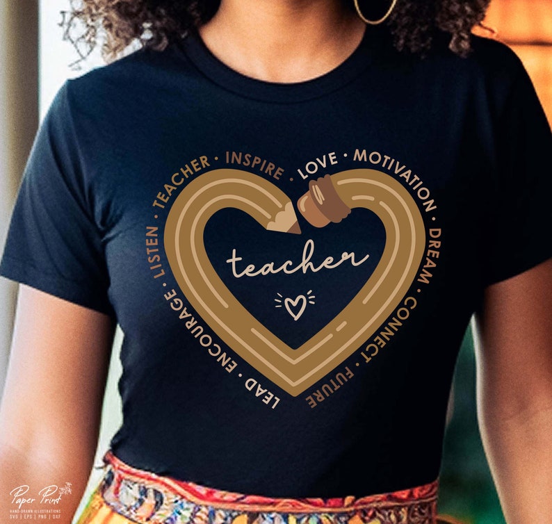 Pu&ograve; includere: Una maglietta nera con un design a forma di cuore dorato che presenta una matita e la parola "teacher" all'interno del cuore. Il cuore &egrave; circondato dalle parole "Teacher, Inspire, Love, Motivation, Dream, Connect, Future, Lead, Encourage, Listen".