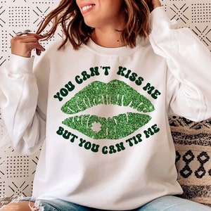 May include: White sweatshirt with green glitter lips and the text "You can't kiss me but you can tip me".