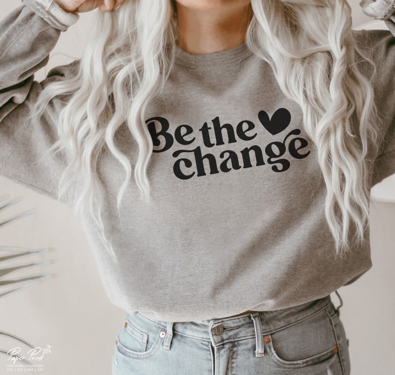 Puede incluir: Una sudadera gris con el texto "Be the &hearts; change" en negro.