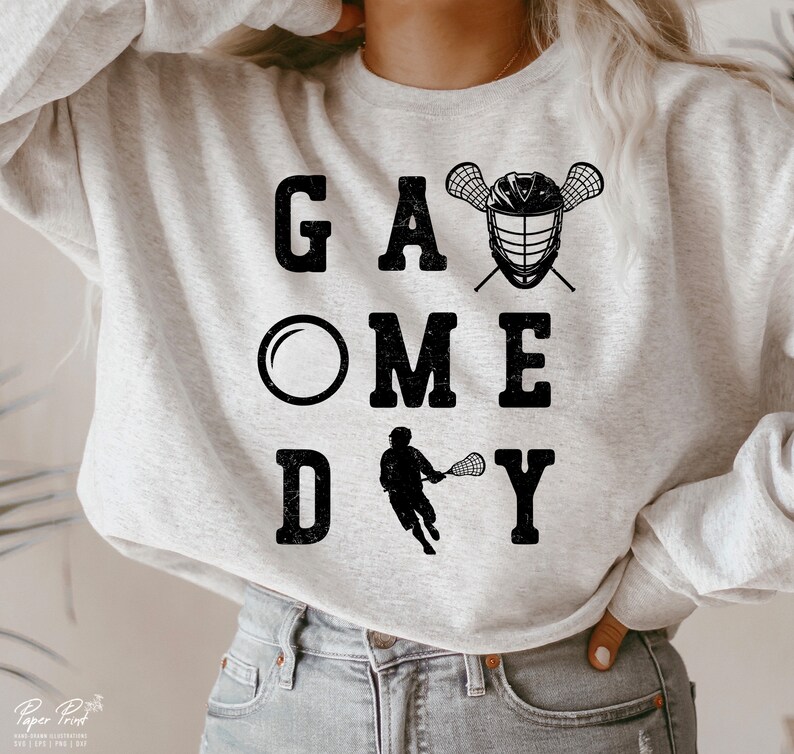 May include: A gray sweatshirt with the text "GAME DAY" in black with a lacrosse stick and helmet graphic.