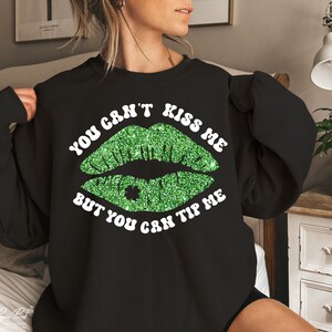 May include: Black sweatshirt with a green glitter lip print and the text "You can't kiss me but you can tip me".