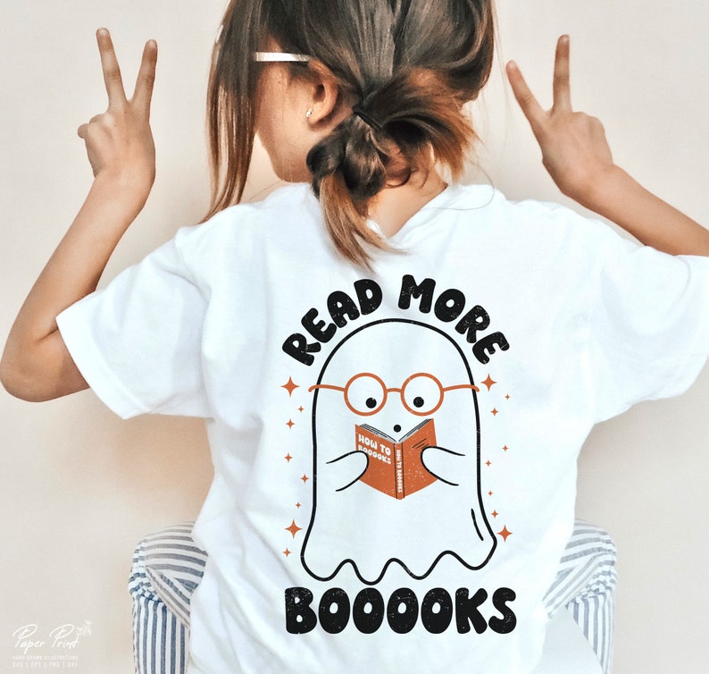 May include: White t-shirt with a ghost wearing glasses and reading a book that says "How to Boooks". The text on the shirt says "Read More Booooks".