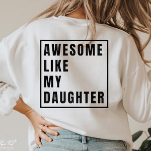 May include: White sweatshirt with black text that reads "Awesome Like My Daughter" in a square frame.