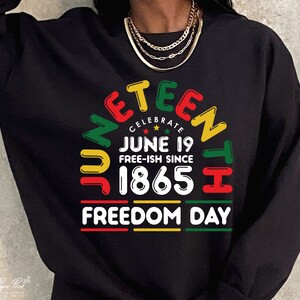 May include: Black sweatshirt with a colorful graphic design that says "Juneteenth Celebrate June 19 Free-ish Since 1865 Freedom Day".