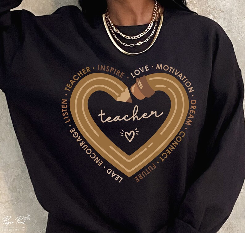 Pu&ograve; includere: Felpa nera con una grafica marrone di una matita a forma di cuore. Il cuore contiene la parola "teacher" all'interno ed &egrave; circondato dalle parole "lead, encourage, listen, teacher, inspire, love, motivation, dream, connect, future".