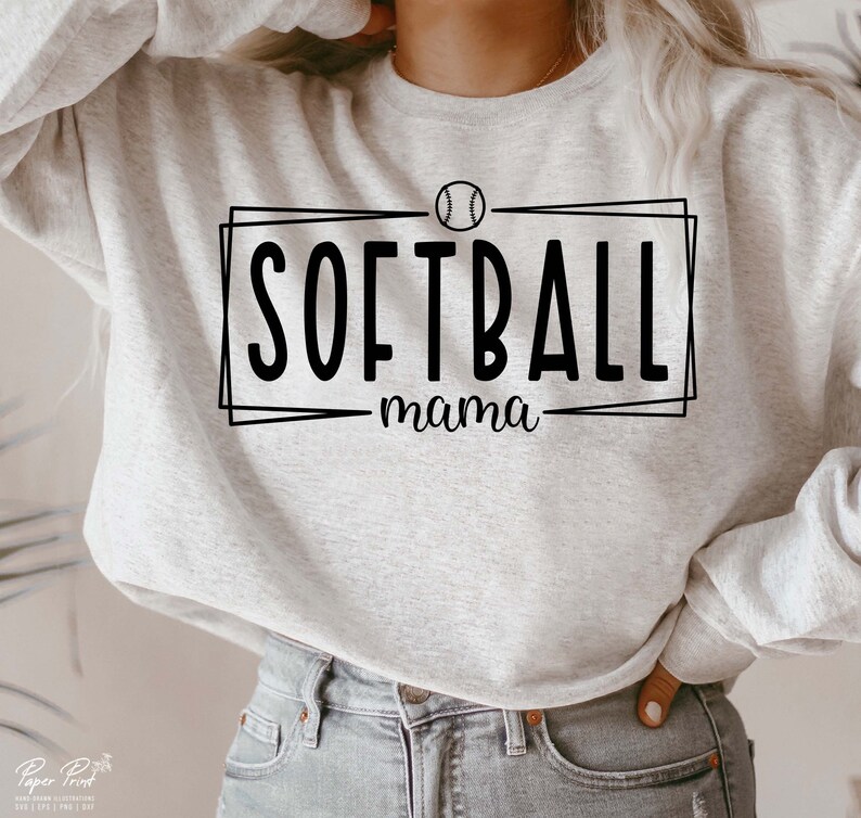 Pu&ograve; includere: Felpa grigio chiaro con la scritta nera "SOFTBALL mama", con una grafica di softball sopra la parola "SOFTBALL". La felpa &egrave; a girocollo.