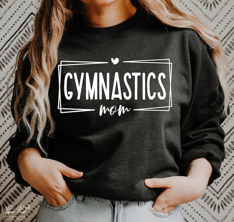 May include: Black sweatshirt with the words "GYMNASTICS mom" in white, inside a white rectangular frame. A small white heart is above the word "mom". The sweatshirt is a crew neck style.