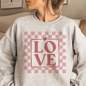 May include: A grey sweatshirt with a pink and white checkered pattern and the word "LOVE" in a pink box.