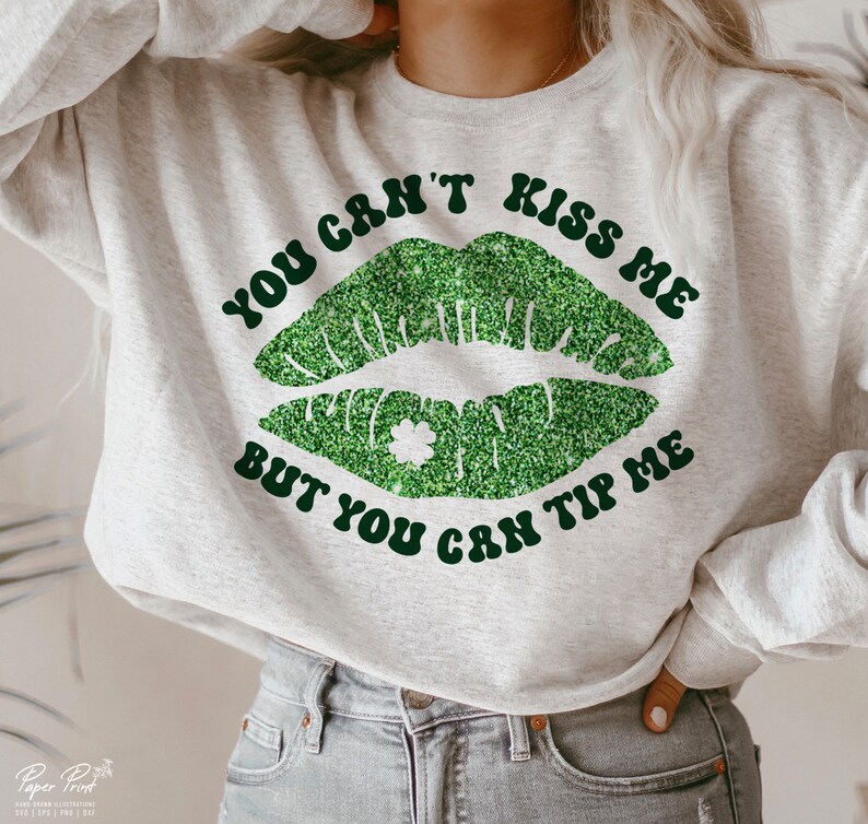 May include: A gray sweatshirt with the text "You can't kiss me but you can tip me" in black with a green glitter lip design and a shamrock.