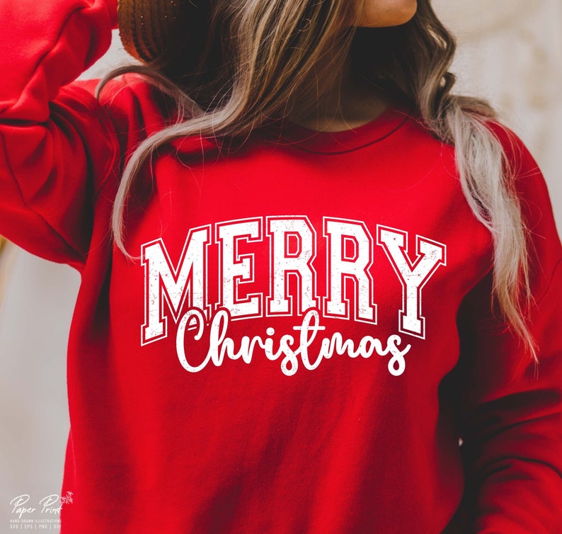 K&ouml;nnte beinhalten: Roter Pullover mit einem wei&szlig;en, abgenutzten Aufdruck, der "Frohe Weihnachten" sagt.