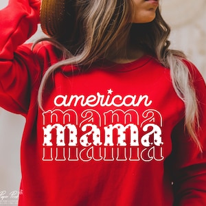 Pode incluir: Camisola vermelha com texto branco que diz "american mama" com estrelas nas letras.