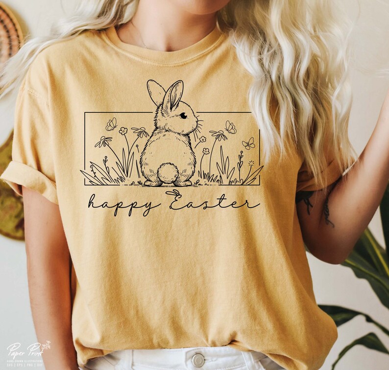 May include: A yellow t-shirt featuring a black line drawing of a bunny rabbit in a field of flowers. The text "happy Easter" is written below the bunny.