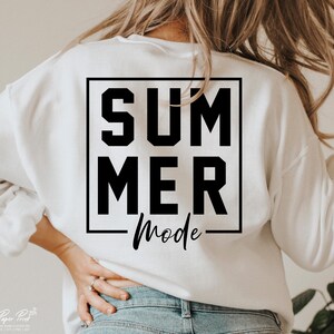 May include: White sweatshirt with the words "SUMMER Mode" printed in black. The text is inside a black square. The sweatshirt is a casual style, perfect for warm weather.