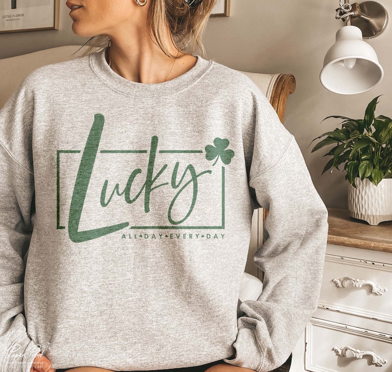 May include: Gray sweatshirt with a green shamrock and the text "Lucky All Day Every Day" in a white box.