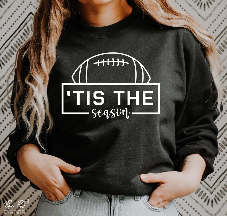 May include: Black sweatshirt with a white outline of a football and the text 'Tis the season'.