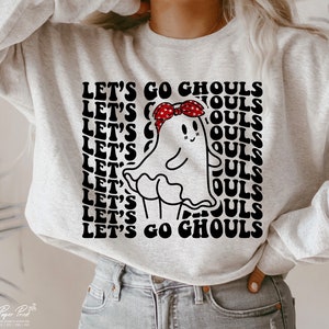 May include: A grey sweatshirt featuring a black and white graphic of a ghost wearing a red bandana. The text "Let's Go Ghouls" is repeated in a retro font.