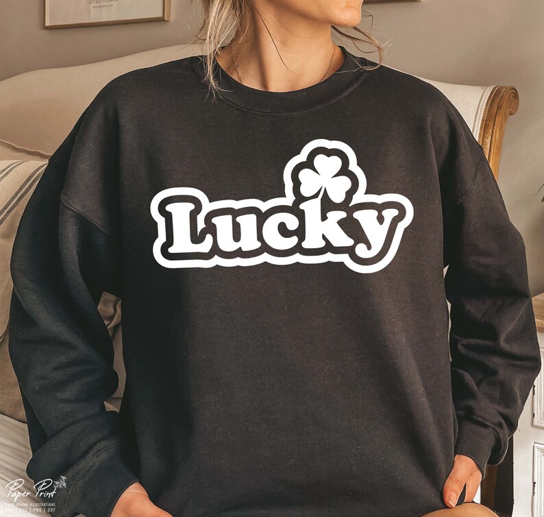 May include: Black sweatshirt with a white graphic of a four-leaf clover and the word "Lucky" in a retro font.
