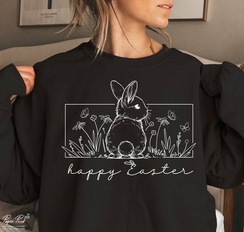 May include: Black sweatshirt featuring a white outline of a rabbit in a field of flowers and butterflies. The text "happy Easter" is written below the image.