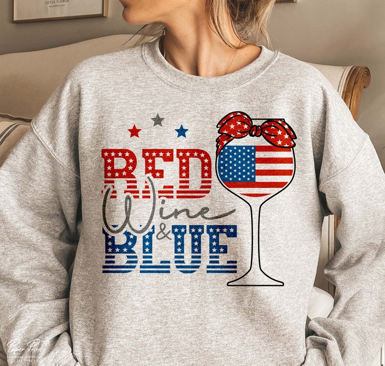 K&ouml;nnte beinhalten: Grauer Pullover mit einem roten, wei&szlig;en und blauen Weinglas-Motiv. Das Glas hat eine rote, wei&szlig;e und blaue Schleife oben und den Text "Red Wine & Blue" in rot, wei&szlig; und blau.