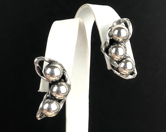 May include: A pair of silver earrings shaped like pea pods with three round beads in each pod.