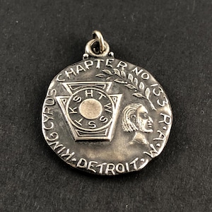 May include: A silver-colored pendant with the text "CHAPTER NO 133 R.A.M." and "CYRUS KING DETROIT W.V." The pendant features a central emblem with the letters "K.S.H.W.S." and a profile of a person.