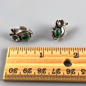 May include: A pair of sterling silver earrings featuring green malachite stones and floral designs. The earrings are approximately 2.5 cm long and are displayed next to a ruler for scale.