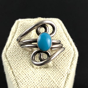 Puede incluir: Un anillo de plata con una piedra turquesa azul engastada en un diseño de espiral.