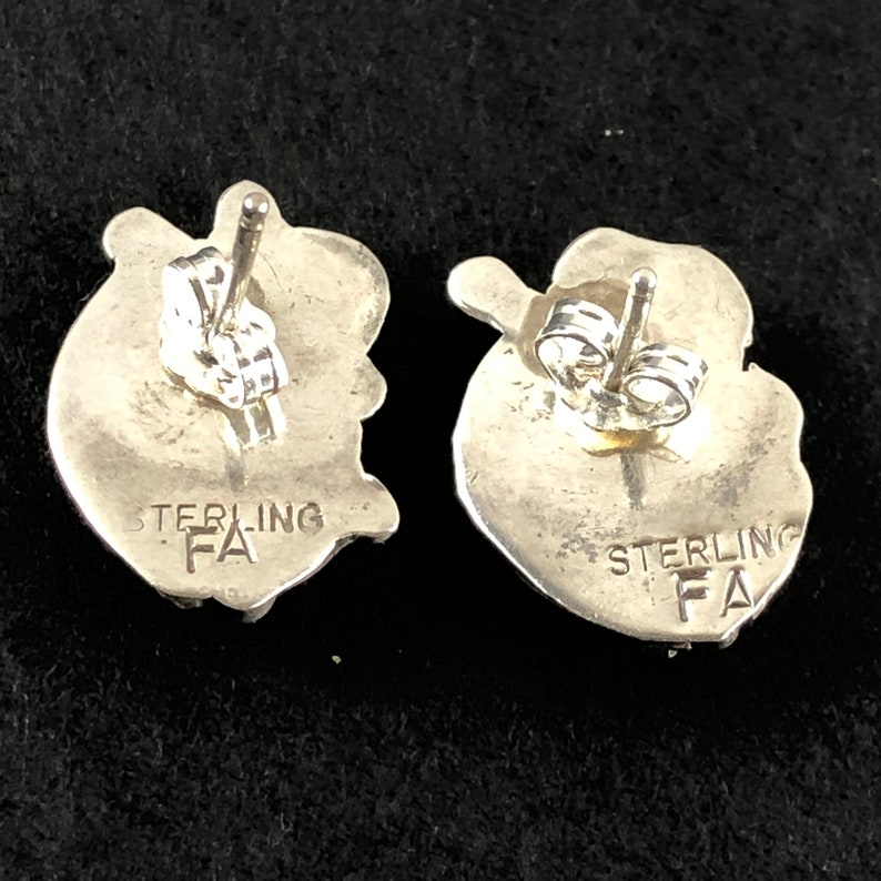 May include: A pair of silver earrings with a heart shape and the text "STERLING FA" on the back.