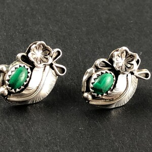 May include: A pair of silver earrings featuring green malachite stones and a floral design.