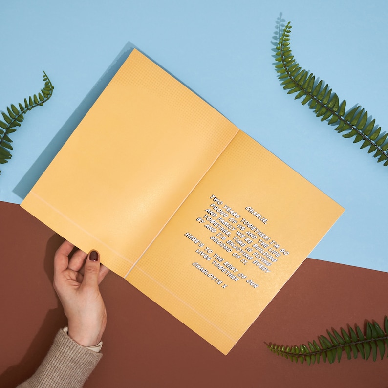 May include: A yellow card with a handwritten message that reads "Charlie, Two years together! I'm so proud of us and the life and family we're building together. Time is flying by and I'm enjoying every second of it. Here's to the rest of our lives together. Charlotte X."