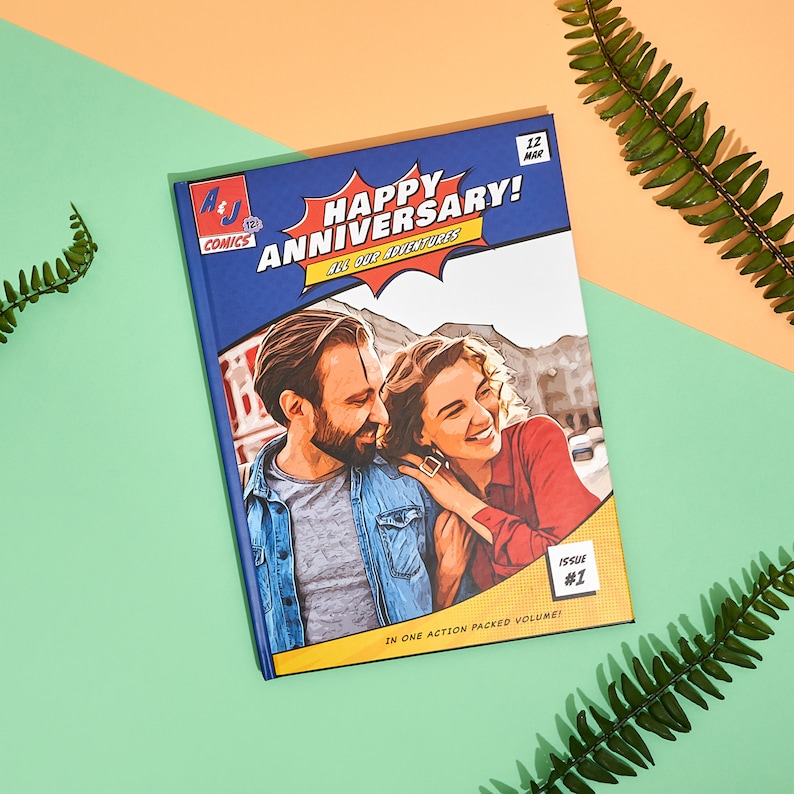 May include: A blue comic book cover with the text "Happy Anniversary! All Our Adventures" in a yellow speech bubble. The cover features a couple in a cartoon style with the text "Issue #1" in a yellow box.