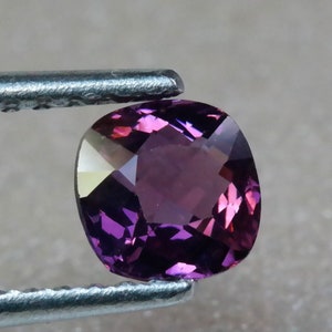 Pu&ograve; includere: Una pietra preziosa viola a taglio cuscino con una superficie sfaccettata.