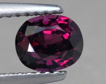 May include: A deep purple oval-shaped gemstone with a faceted cut.