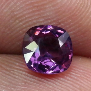 Pu&ograve; includere: Una pietra preziosa viola a taglio cuscino con una superficie sfaccettata.