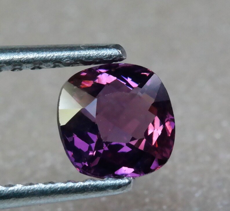 Pu&ograve; includere: Una pietra preziosa viola a taglio cuscino con una superficie sfaccettata.