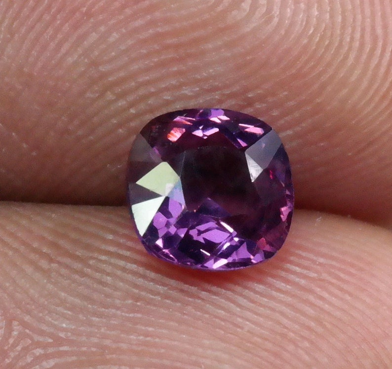 Pu&ograve; includere: Una pietra preziosa viola a taglio cuscino con una superficie sfaccettata.