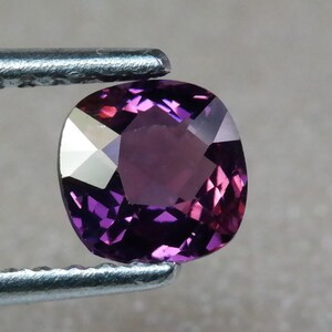 Pu&ograve; includere: Una pietra preziosa viola a taglio cuscino con una superficie sfaccettata.